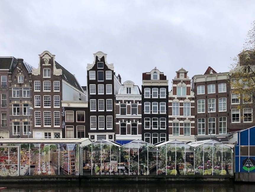 Iconic canal houses and floating Flower Market in Amsterdam, Holland reflect Dutch charm.