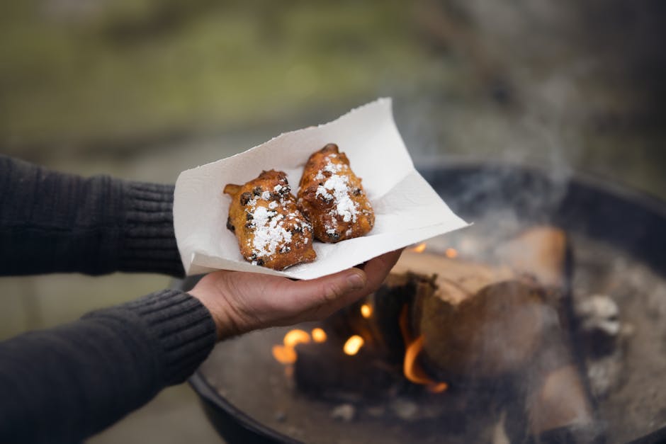 Warm Dutch oliebollen served outdoors near a cozy fire with powdered sugar.