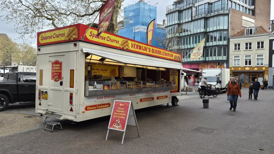 A colorful street food truck in Utrecht selling churros and oliebollen in a lively city square.